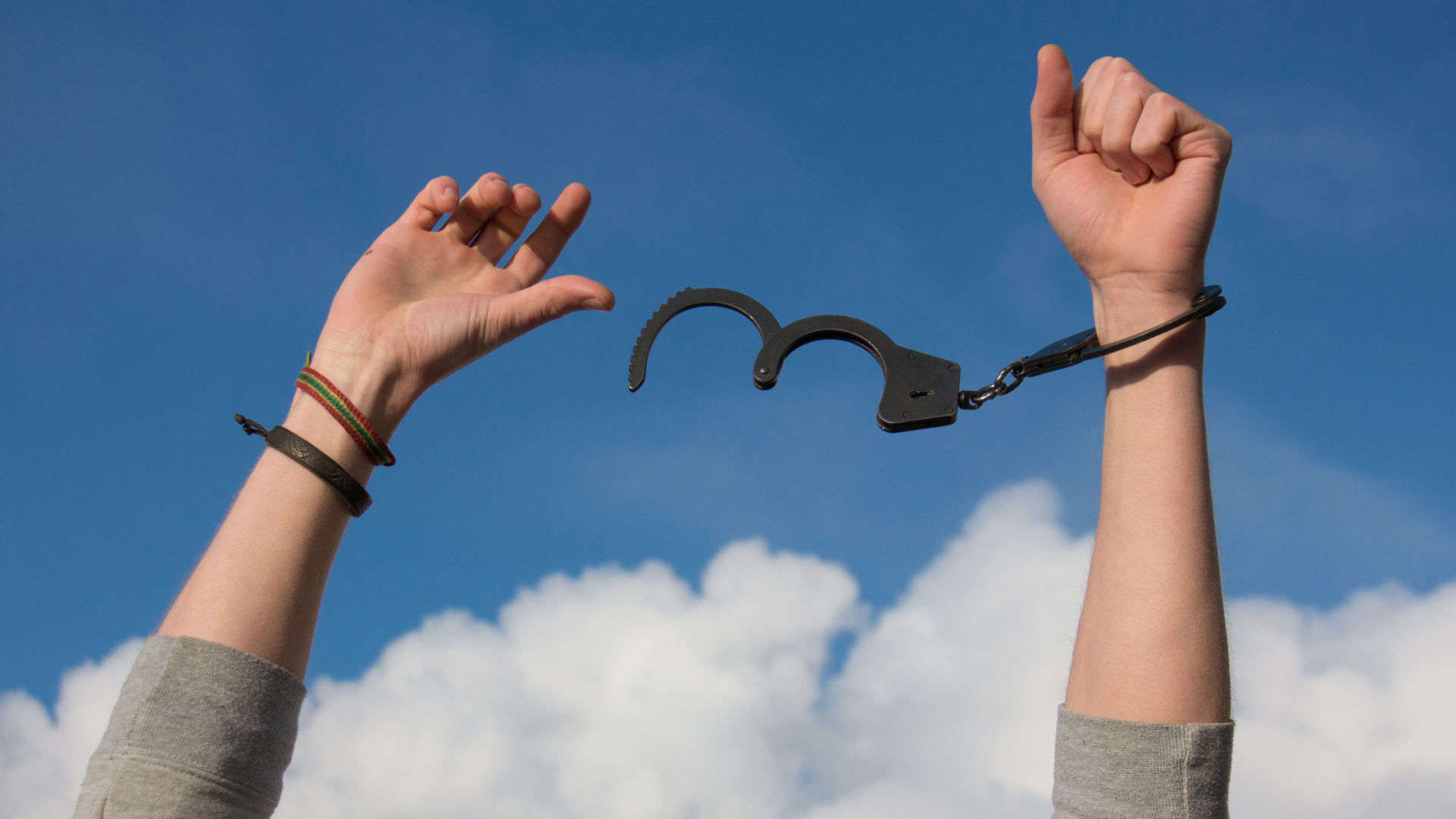 2 hands in the sky with one hand being freed from handcuffs