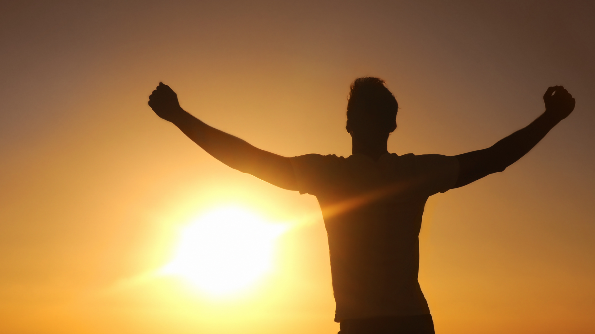 man with his arms wide open and triumphant looking into the sun